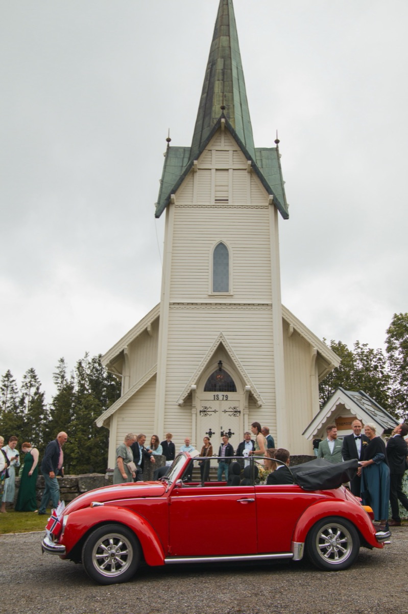 Rød bryllupsbil utenfor norsk kirke — klassisk lokale-valg